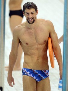 Man in swim trunks holding a kickboard.